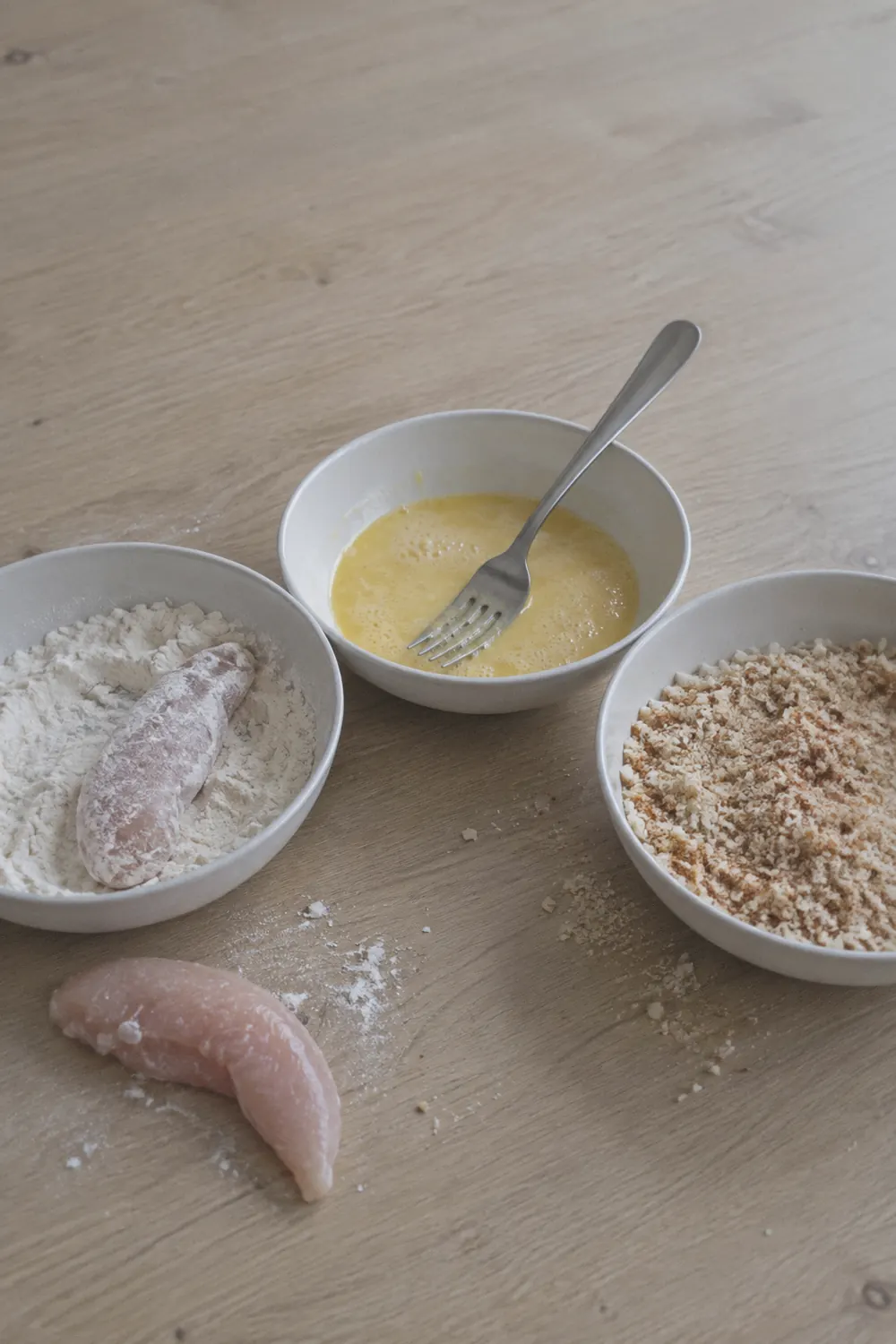 Breading station with three bowls of flour, egg, and panko mixture