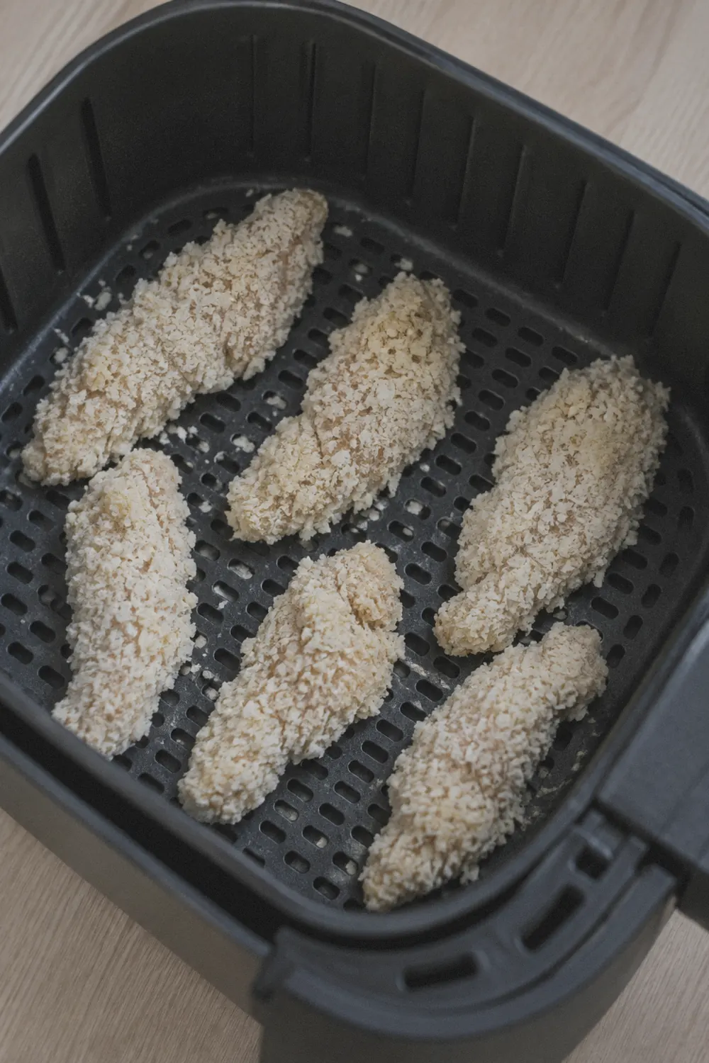 Golden chicken tenders arranged in an air fryer basket
