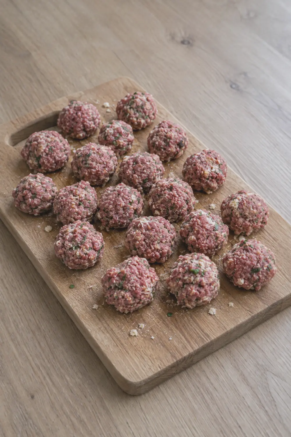Rows of raw meatballs on a cutting board ready to go into the air fryer