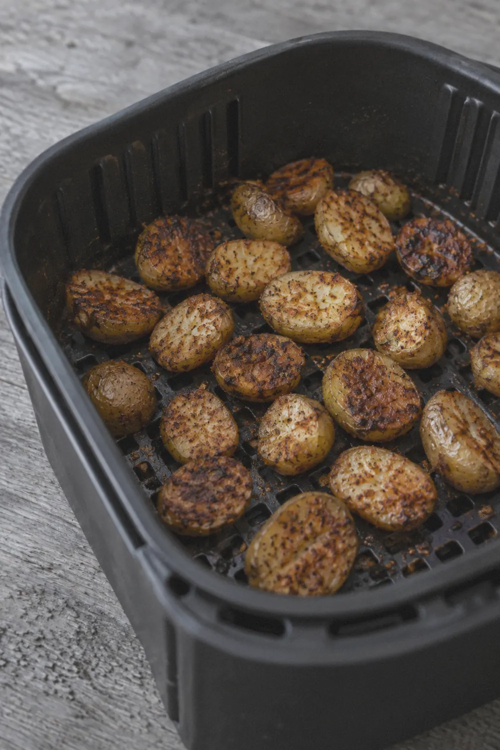 Crispy golden potatoes in an air fryer basket after cooking