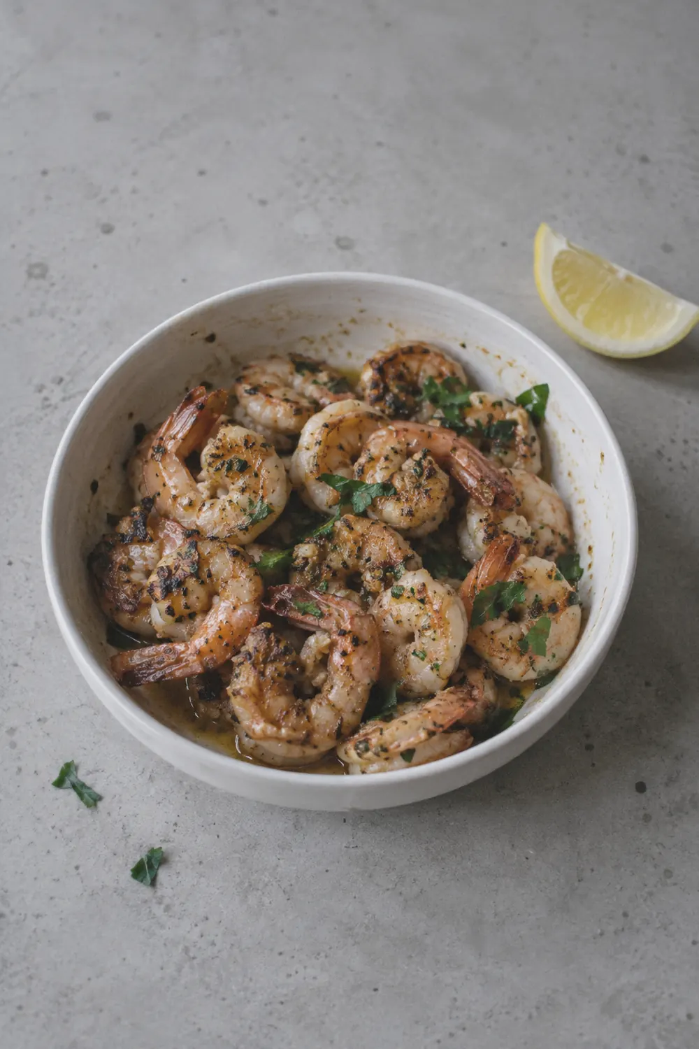 Finished air fryer shrimp in a bowl with curled tails and parsley