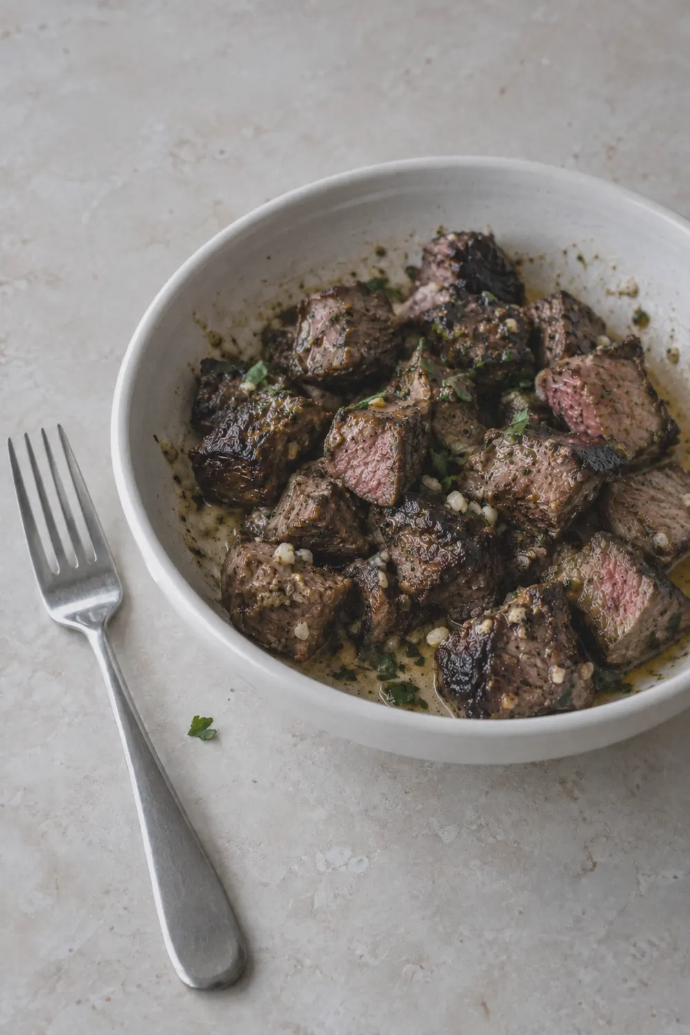 Finished air fryer steak bites in a bowl with seared edges and parsley