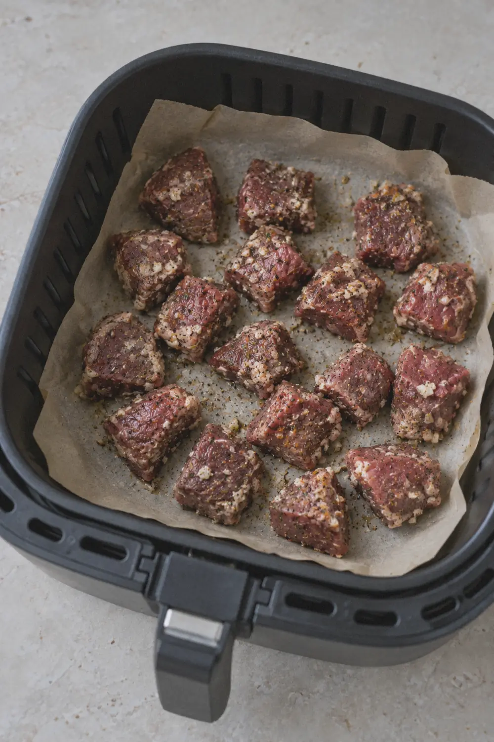 Steak bites spread in a single layer inside the air fryer basket before cooking