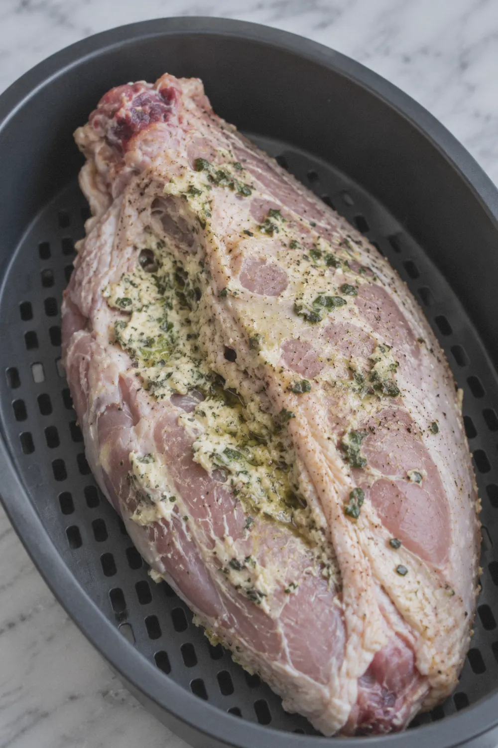 Seasoned turkey breast placed skin side down in the air fryer basket ready to cook