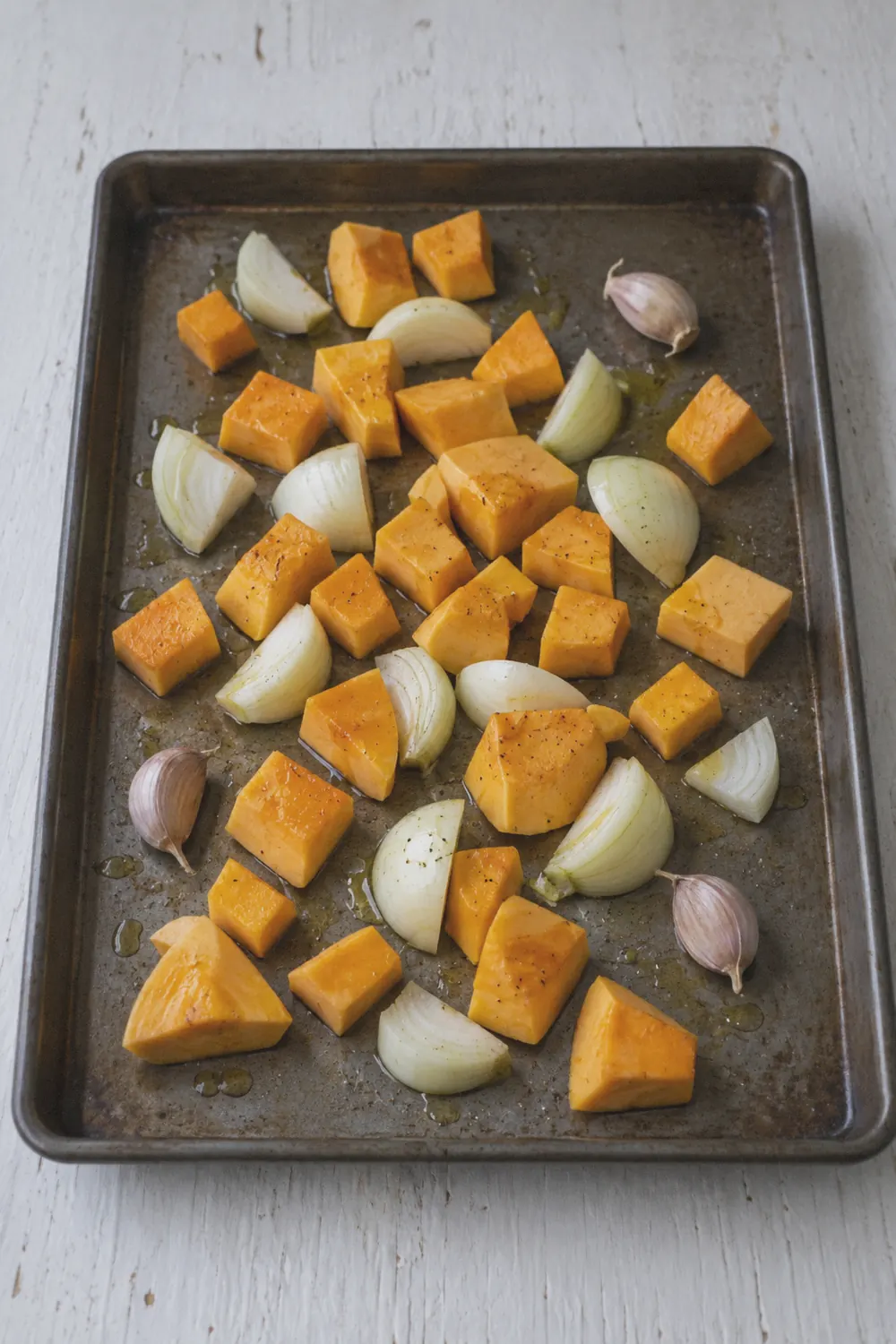 Cubed butternut squash and onion on a baking sheet before roasting