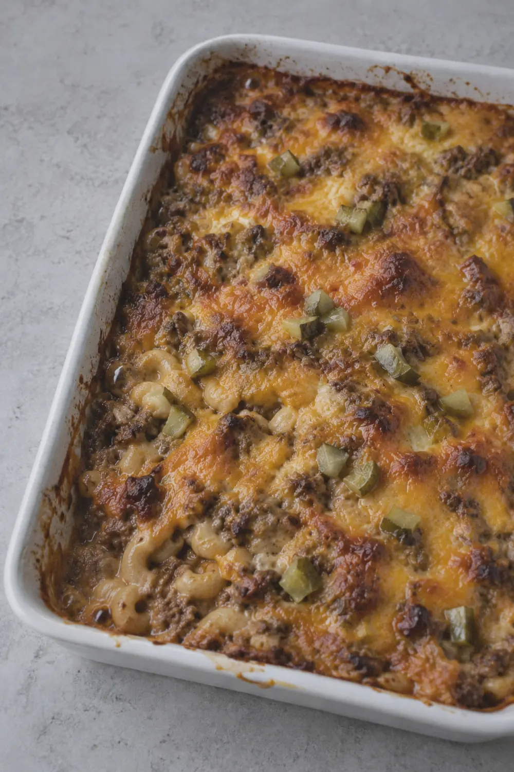 Baked cheeseburger casserole fresh from the oven with melted browned cheddar and pickle pieces visible on top