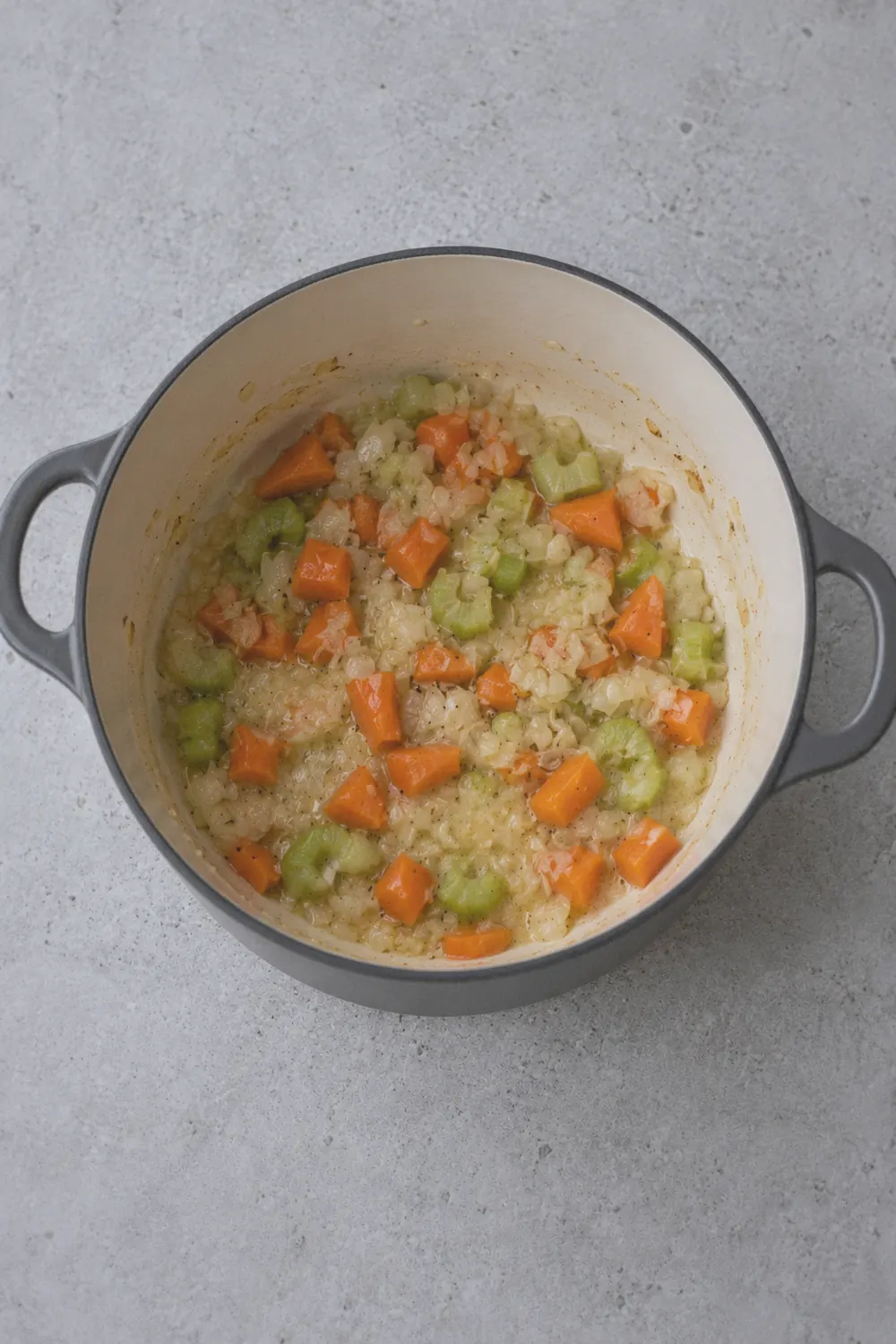 Diced carrots, celery, and onion cooking in butter in a Dutch oven