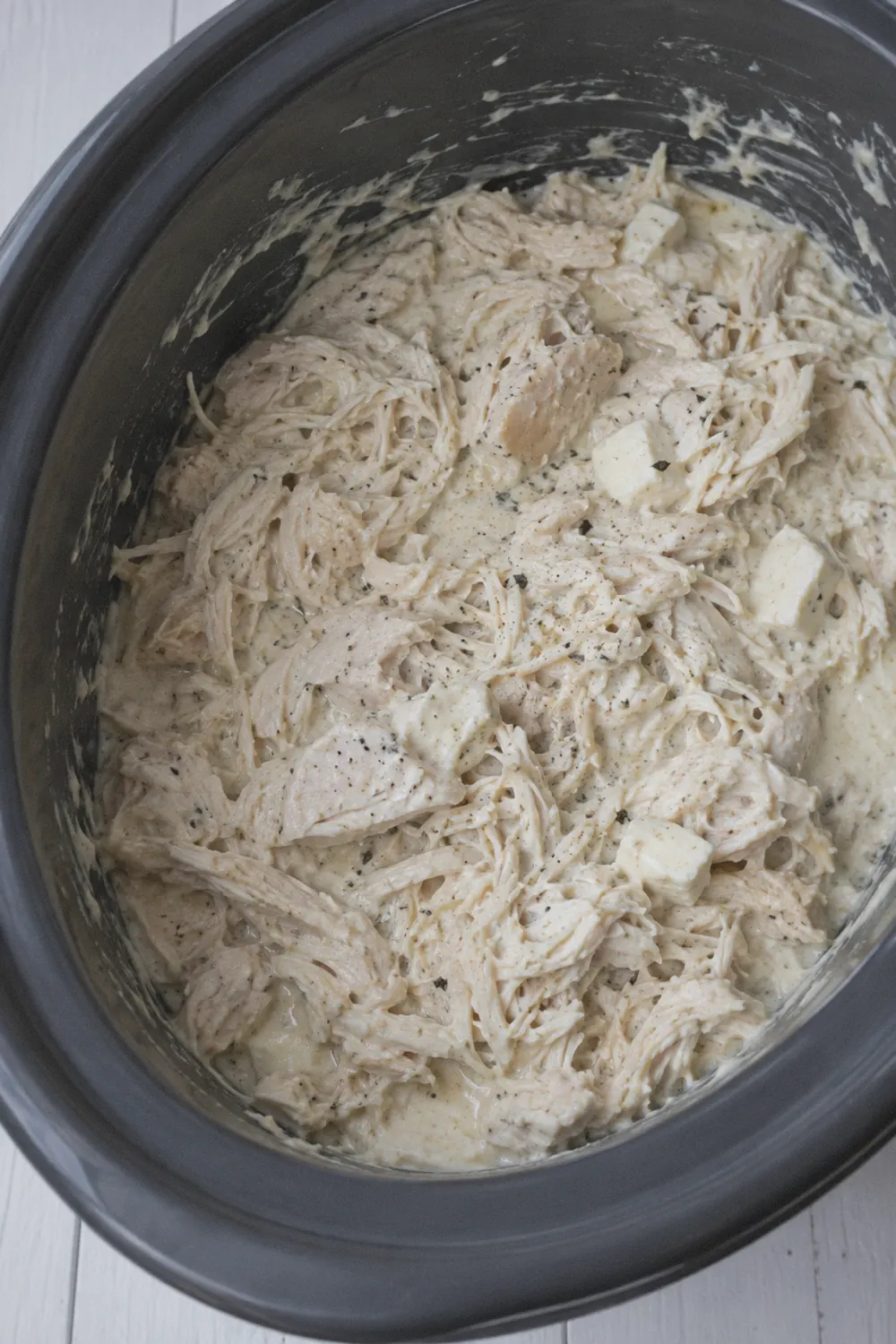 Shredded chicken stirred into creamy alfredo sauce in the slow cooker