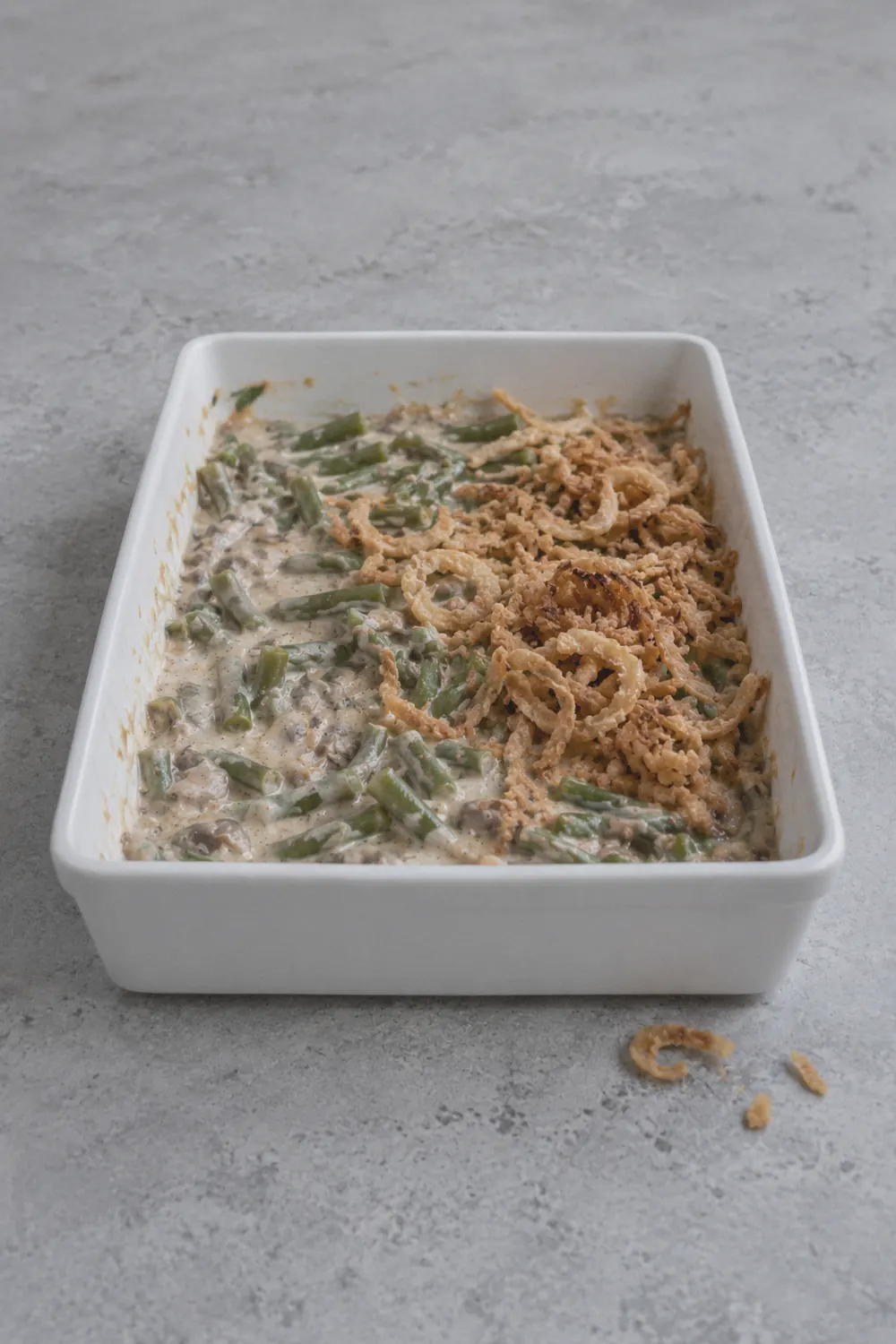 Green bean casserole ingredients mixed in a white ceramic baking dish