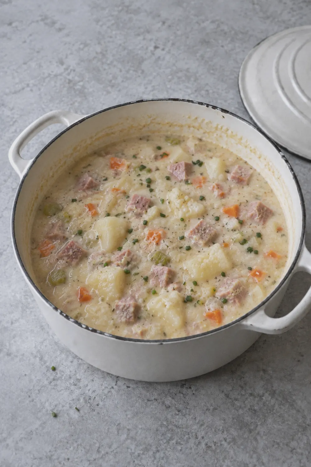 Finished creamy ham and potato soup in a Dutch oven with a thick pale broth, chunks of ham and potato, and a few pieces of potato partially mashed into the liquid