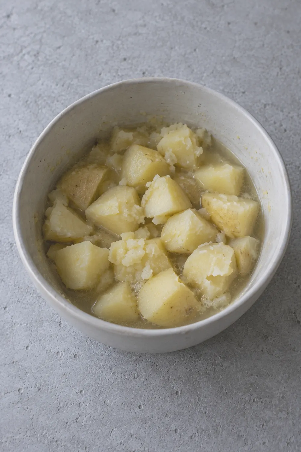 Yukon Gold potato chunks in the open Instant Pot after pressure cooking, visibly soft and starting to break apart at the edges, steam rising from the pot, a few pieces cracked open showing the fluffy interior