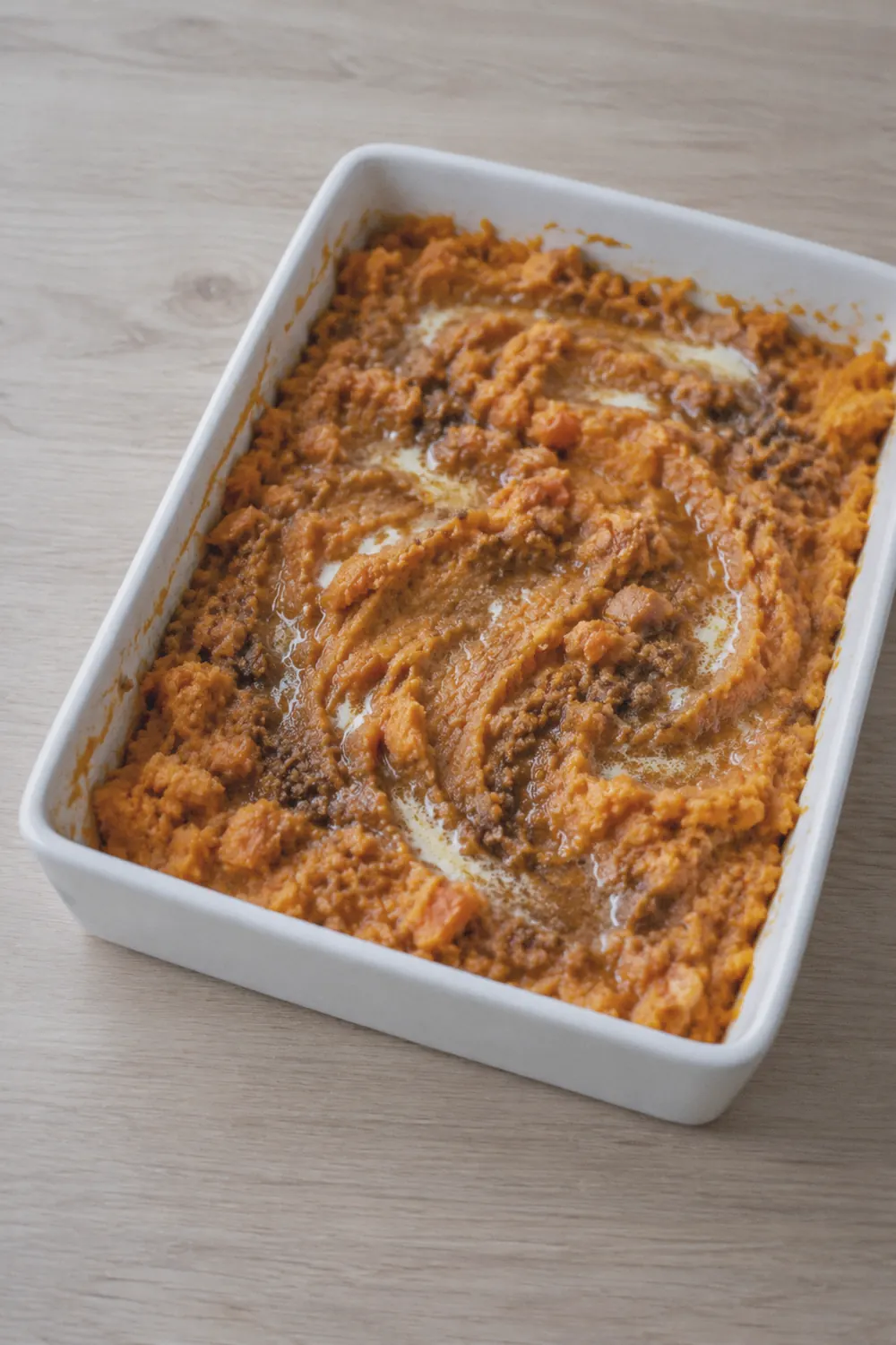 Sweet potato casserole ingredients with mashed sweet potatoes in a bowl and pecan streusel mixture beside it