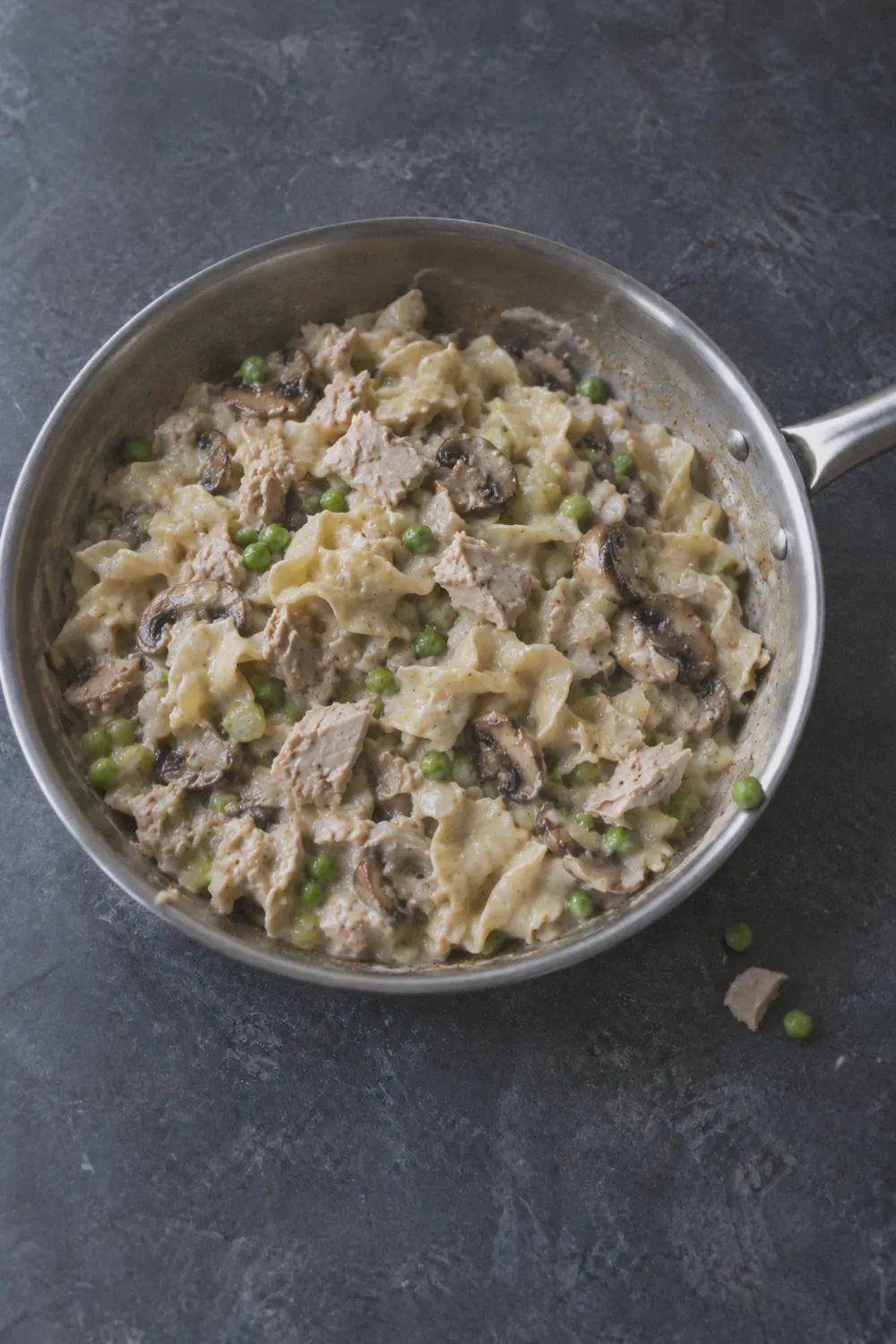 Creamy mushroom sauce with melted cheddar coating egg noodles and flaked tuna in a skillet